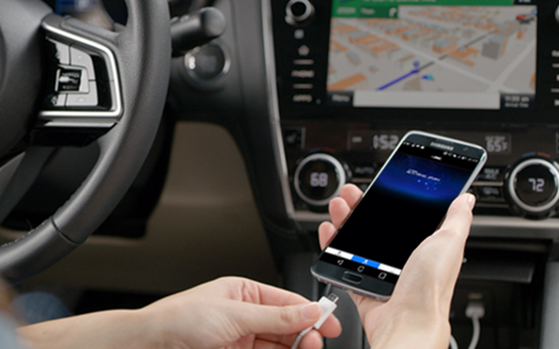 A smartphone with the SUBARU STARLINK app in use while being plugged into a Subaru’s in-vehicle multimedia touchscreen.